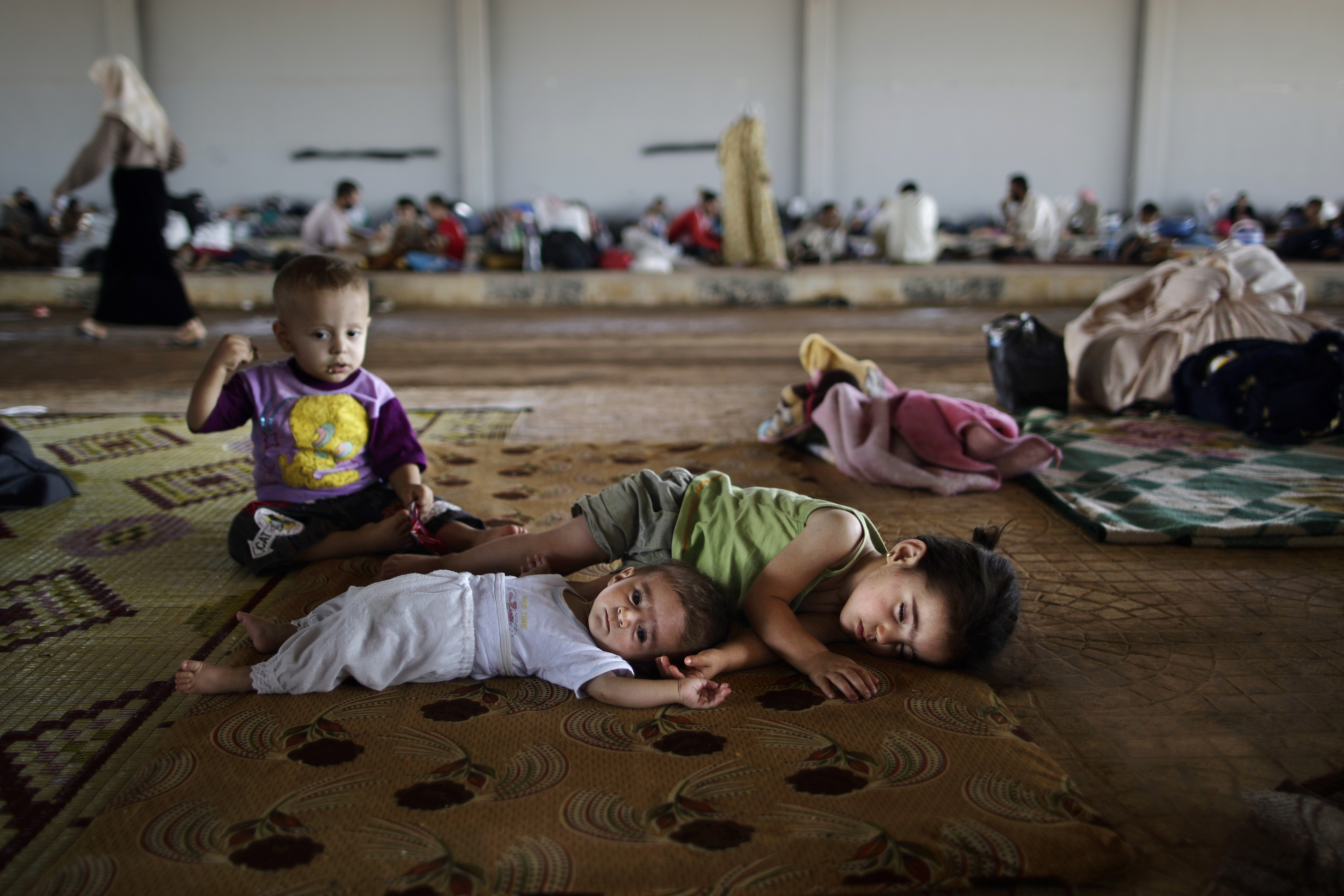 En esta imagen de archivo del 26 de agosto de 2012, niños sirios que huyeron de sus casas con su familia debido a los combates entre los rebeldes y el ejército, tumbados en el suelo en el cruce de frontera de Bab Al-Salameh, desde donde esperan llegar a uno de los campos de refugiados en Turquía, cerca de la ciudad siria de Azaz. (AP Foto/Muhammed Muheisen, Archivo)
