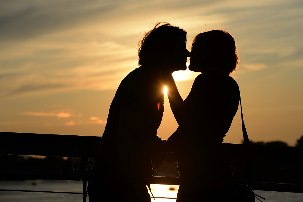 Una bareja besándose durante una puesta de sol.